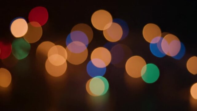 Realistic camera lens bokeh animation showing soft defocused light circles floating slowly warm orange red blue and subtle green colors blending naturally creating a glowing gradient effect dark backg