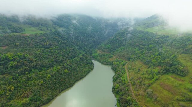 Lago verde entre montanhas, nuvens e florestas. Drone. 4K.