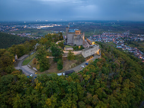 Aerial view of Hambach Castle perched atop a forested hill, its ancient stones illuminated against the fading twilight, Neustadt an der Weinstrasse, Rheinland-Pfalz, Germany.