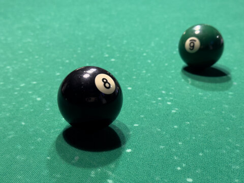 Billiard table close-up showing eight and nine balls arranged on green felt under bright lights in a leisure setting for strategic gameplay