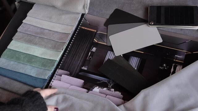female designer selects beige fabric from fabric samples for curtains, textiles and furniture. professional selection of fabric in the salon, interior design, cozy home, tactile sensation