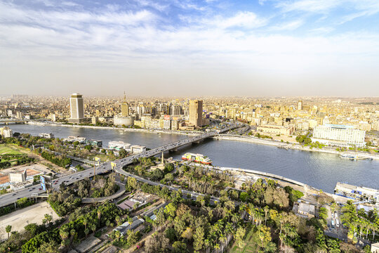 View of the Nile River snaking through the urban sprawl, bridges connecting the city's districts under a vast sky, blending history and modernity, Cairo, Cairo Governorate, Egypt.