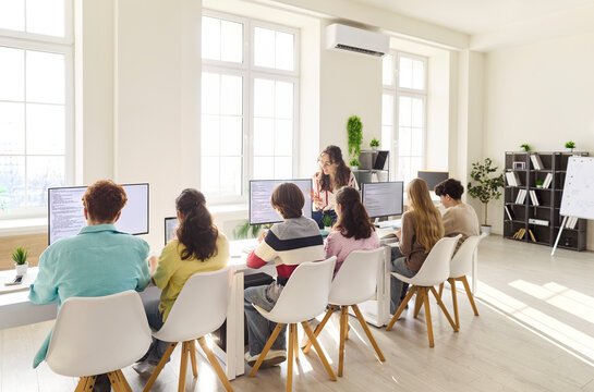 Students teenagers teacher coding programming computer classroom. Teens work at monitors as an instructor leads tasks, building code skills in a bright space. Clear theme of digital learning.