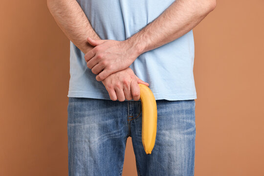 Urology. Man with banana on beige background, closeup