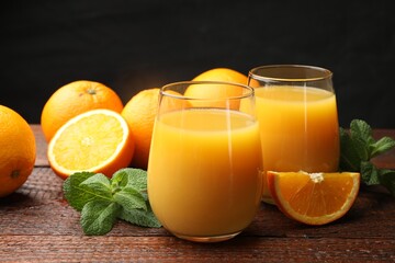 Citrus juice in glasses, fresh oranges and mint leaves on wooden table, closeup © New Africa