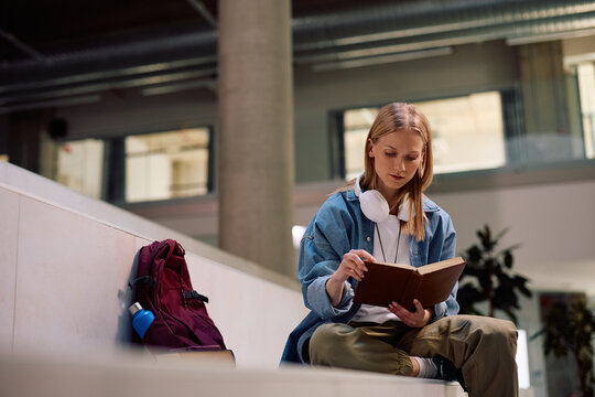 University student studying from book at lecture hall.