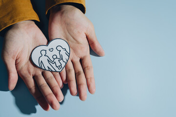 Hands hold heart shaped drawing depicting family, symbolizing love and togetherness. image conveys warmth and connection, emphasizing importance of family bonds © JK_kyoto