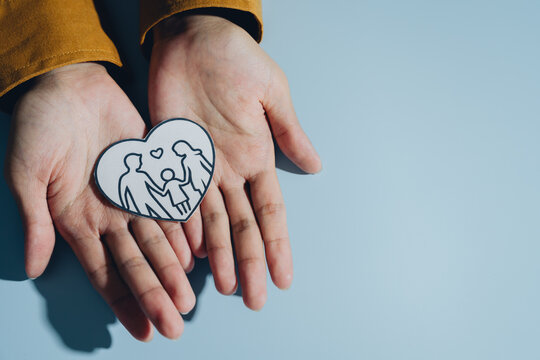 Hands hold heart shaped drawing depicting family, symbolizing love and togetherness. image conveys warmth and connection, emphasizing importance of family bonds