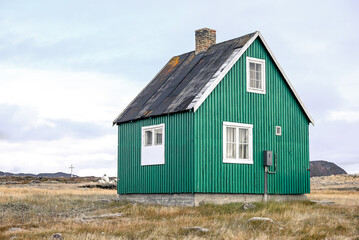 Obraz premium Ilimanaq, Disko Bay, Greenland - Green House in Remote Ilimanaq Greenland with Arctic Tundra and Cross, Minimal Landscape Scene