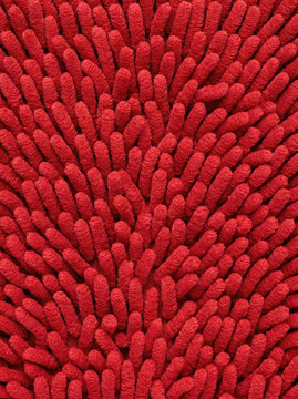 Close-up of vibrant red textured microfiber bathroom rug with soft chenille pattern providing anti-slip surface and luxurious design