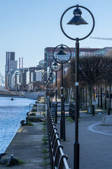 Naklejka premium Street lamps line riverwalk beside Dublin skyline