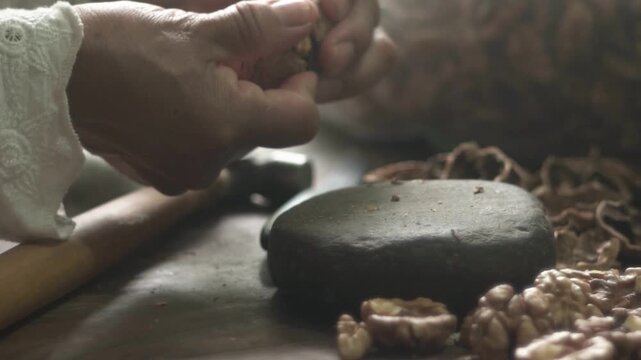 se&ntilde;ora mayor abre nuez con martillo y piedra