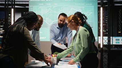 Naklejka na ściany i meble Diverse group of professionals review files and performance metrics, using projections and budgeting to align the company goals with stakeholder expectations for company progress. Camera A.