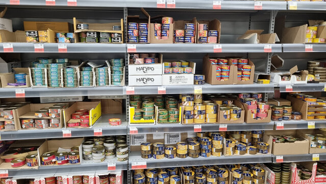 Supermarket shelves with canned food and fish products in retail store