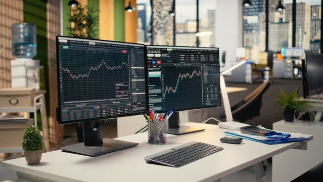 Trading software in prop firm office with price graphs and technical indicators visible on screens. Desktop setup for financial experts tracking stock market activity using analytical tools