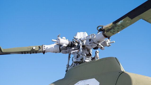 Closeup Helicopter Rotor Hub Exposed Components Against Clear Blue Sky Showing Weathered Paint, Grease And Bolts, Detailed Swashplate And Pitch Control Linkage, Visible Gearbox Elements