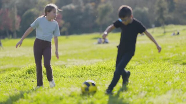 Young boy tripping and falling while playing soccer with friends