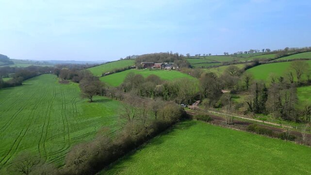 Crediton, Devon, England: DRONE VIEWS: The drone flies over fields, the railway line linking Barnstaple and Exeter and then on towards farm buildings. Crediton is located 7 miles north west of Exeter.