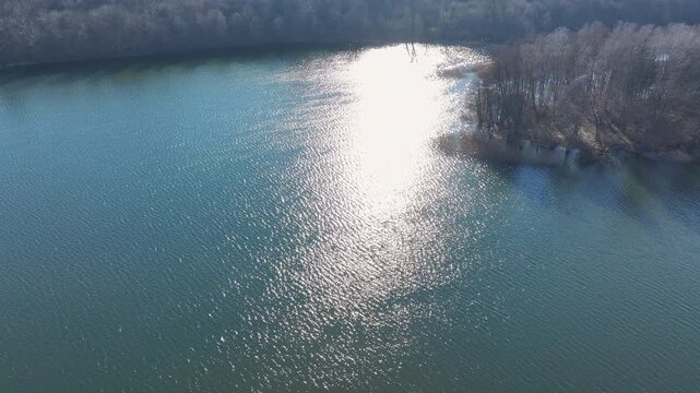 Aerial rural northern Poland lake sun reflection. North west Poland. Spring season, Trails, rivers and lakes. Shore grass and forest on the edge of the water. Farm rural nature landscape. Recreation. 