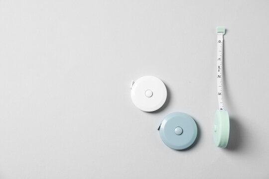 Measuring tapes on light grey background, flat lay. Space for text