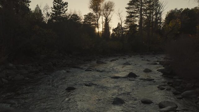 An aerial flyover the Cache La Poudre river with the setting sun near Rustic, CO
