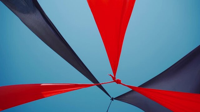 abstract view of red and black triangle shaped cloth decoration waving by wind on blue sky background. summer sea camp or beach club decoration, vibrant colors