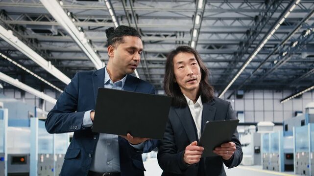 Studying manufacturing gear, microchip factory and multiracial team of managers. Overseeing semiconductors, brainstorming and multiethnic management executives in PCB production plant, camera A