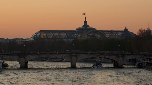 The Grand Palais and the river La Seine in Paris with the orange sky of sunset  
