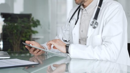 Doctor man in white coat using tablet, working with patient medical records and digital health...