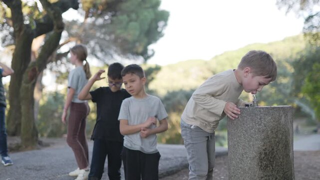 Thirsty young boy drinking from public water fountain