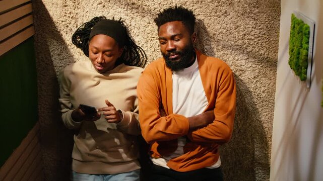 Top down view of black man and woman laughing together on hallway floor, cozy moment of laughter and romance under daylight. Couple bonding and spending quality time, positive relationship.