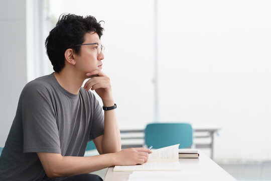 資格を取得する為の講義室で教科書や参考書といった資料を手元に講義を受講する男性