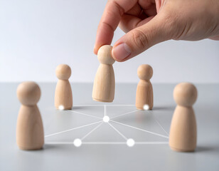 Obraz premium Hand placing wooden figure among other figures connected by lines, symbolizing networking and collaboration.