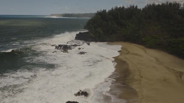 An aerial flyover of Waikoko beach with crashing waves, Kauai, Hawaii