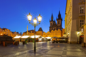 Obraz premium Old Town Square in Prague with historic buildings and Church of Our Lady before Tyn at dawn with early lights and market stalls.
