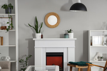 Fototapeta premium Interior of living room with fireplace, shelf units and green plants