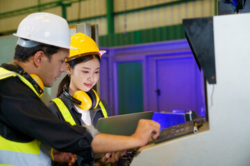 Fototapeta premium Industrial engineers operating machine control panel in factory environment