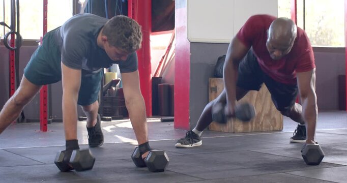 Diverse male partners transitioning from push-up into renegade rows holding hex dumbbells