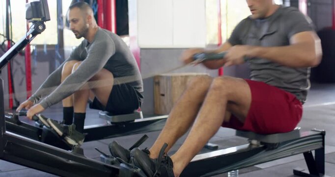 Diverse male partners adjusting straps driving legs, pulling handles at gym to row