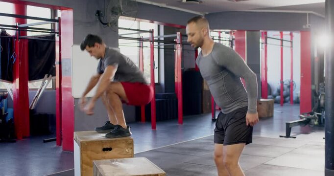 Diverse male workout buo alternating box jumps after knee bend, boosting leg power at gym
