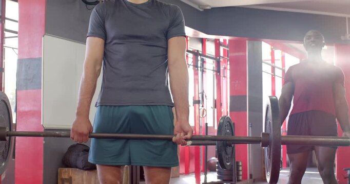 Diverse male workout partners responding to loaded barbell and deadlifting controlled reps