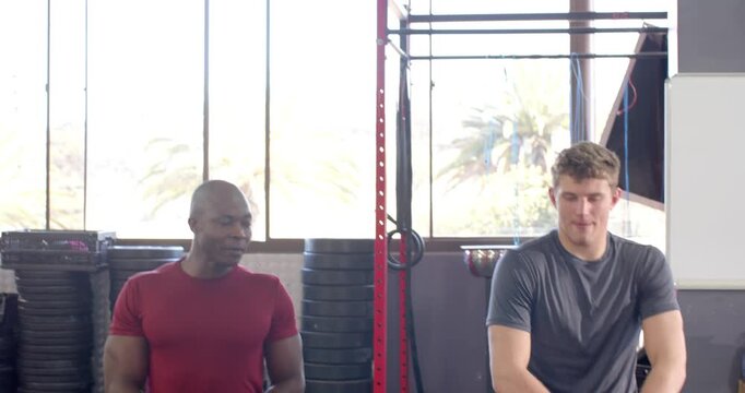 Diverse male trainer and trainee initiating warmup, lifting knee, stretching hips, shuffling