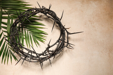 Fototapeta premium Crown of thorns and palm leaves on beige grunge background. Good Friday concept
