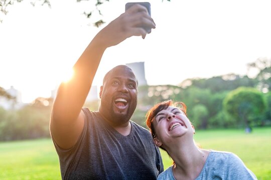 Joyful friends capturing sunset selfie.