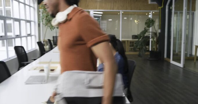 Wheeling white bike into coworking office, man is parking it and unpacking laptop sleeve for work
