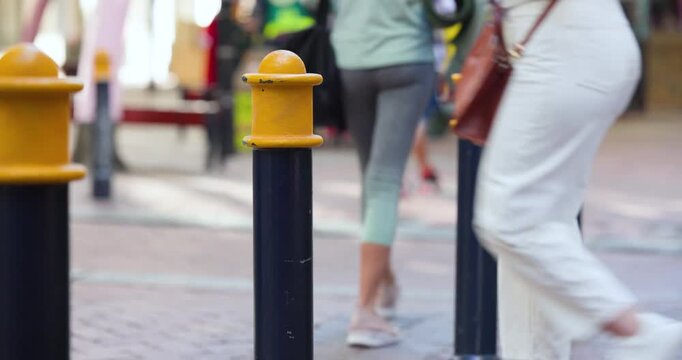Pedestrian flow starting and passing center yellow cap bollard while people are commuting, shopping