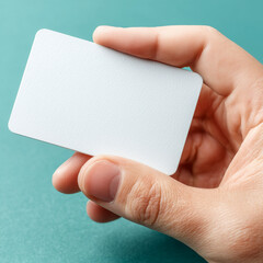 Obraz premium hand holding a blank white card on a teal background