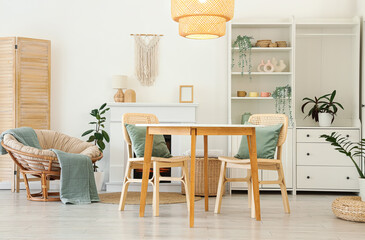 Fototapeta premium Interior of stylish dining room with table, armchair, fireplace and glowing lamp