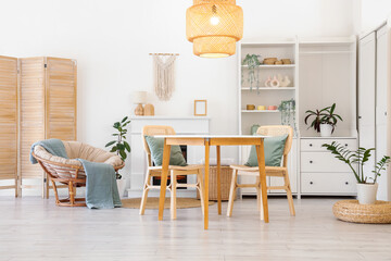 Fototapeta premium Interior of stylish dining room with table, armchair, fireplace and glowing lamp