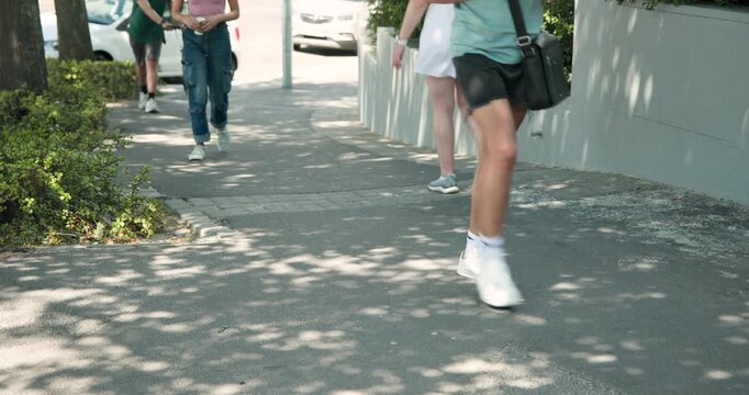 Diverse walkers walking on shaded sidewalk, cyclist dismounting and pushing road bicycle, commuting